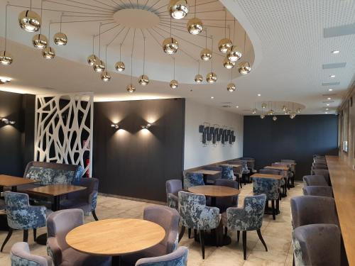 a row of tables and chairs in a restaurant at The Originals Boutique, Hôtel d'Alsace, Strasbourg Sud in Illkirch-Graffenstaden