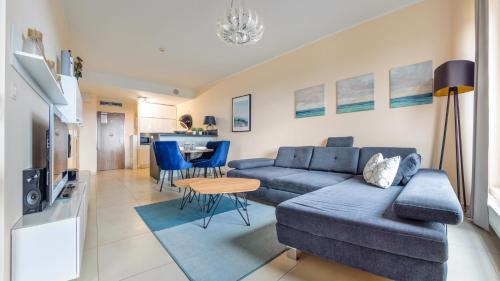 a living room with a blue couch and a table at Olympic Park I, Sun & Snow in Kołobrzeg
