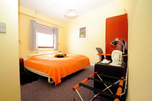 1 dormitorio con 1 cama con manta naranja en Igdlo Guesthouse, en Narsaq