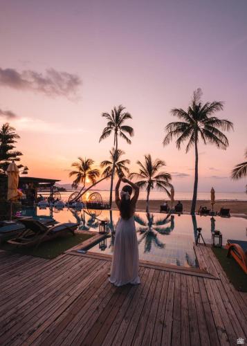 a woman in a white dress standing in front of a pool at Tango Luxe Beach Villa, Koh Samui in Choeng Mon Beach