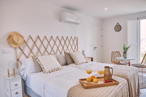 a bed with a tray of fruit and two glasses of wine at ALDARA SUITES in Santiago de Compostela