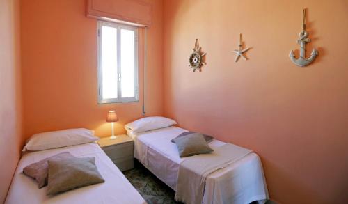 two beds in a room with orange walls and a window at Casa Barca - Le chiavi degli Iblei in Punta Braccetto