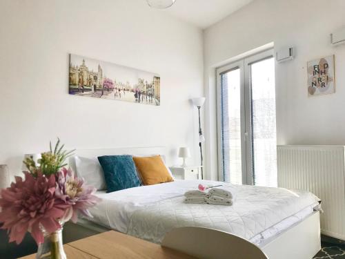 a white bedroom with a bed and a vase with flowers at Apartament Czechowska Luxury in Lublin