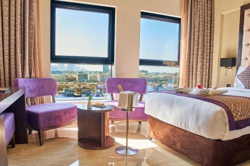 Carlton Dubai Creek Hotel في دبي: غرفة نوم بأثاث أرجواني ونافذة كبيرة