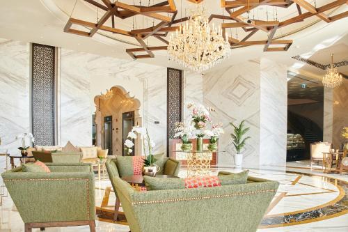 a lobby with green chairs and a chandelier at Carlton Dubai Creek Hotel in Dubai