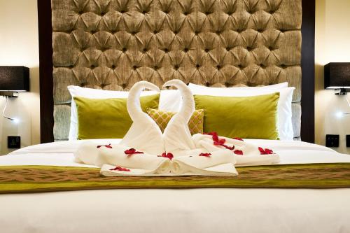 two swans dressed in white are sitting on a bed at Carlton Dubai Creek Hotel in Dubai