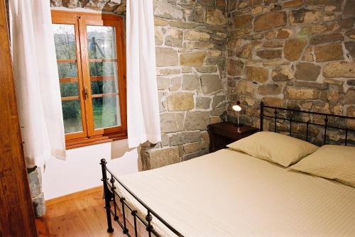 1 dormitorio con cama y pared de piedra en Bordon wines, estate with accommodation, en Dekani