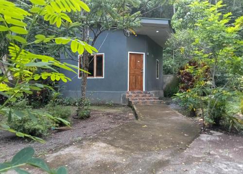 a small blue house with a door in a forest at Tangkoko Ranger Homestay in Bitung