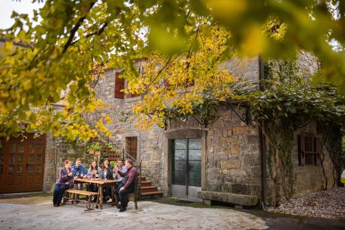 Dekani的住宿－Bordon wines, estate with accommodation，一群人坐在石头建筑前面的桌子上