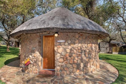 a small stone building with a grass roof at Blyde River Wilderness Lodge in Hoedspruit