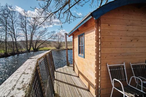 a cabin with a wooden walkway next to a river at Strnadovský mlýn in Jesenice