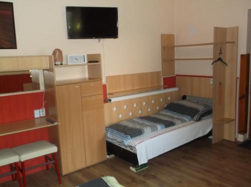 a room with a bed and a tv and shelves at Vali Vendégház in Gyula