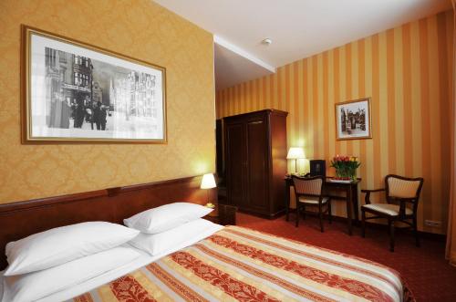 a hotel room with a bed and a table and chairs at Hotel Wolne Miasto Old Town Gdańsk in Gdańsk