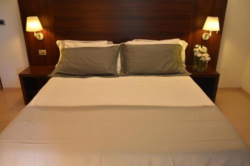 a bedroom with a large bed with two pillows at Delfina Palace Hotel in Foligno