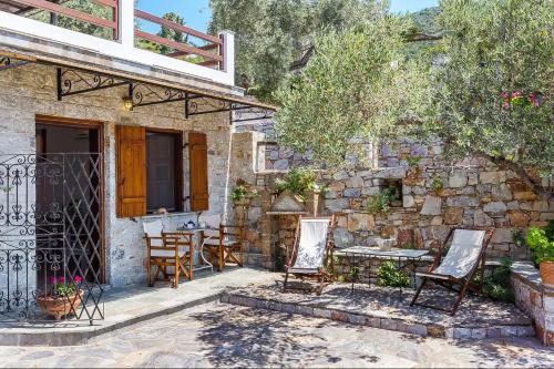 a patio with chairs and tables and a stone wall at Irida Apartments in Stafylos