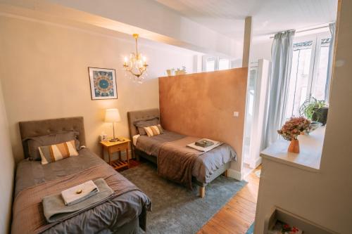 a small room with two beds and a window at La Maison 64 Chambre D'Hôtes in Barbaste