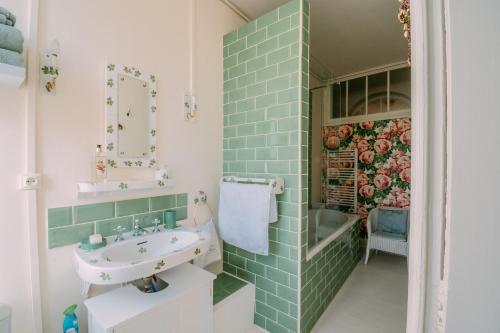 La salle de bains est pourvue de carrelage vert et d'un lavabo. dans l'établissement La Maison 64 Chambre D'Hôtes, à Barbaste