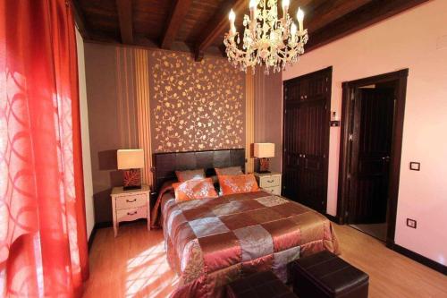 a bedroom with a large bed and a chandelier at El Rosal del Pozo in Argés