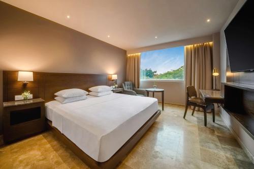 a bedroom with a large white bed and a desk at Hyatt Regency Villahermosa in Villahermosa