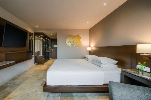 ein Schlafzimmer mit einem großen weißen Bett und einem Flachbildfernseher in der Unterkunft Hyatt Regency Villahermosa in Villahermosa