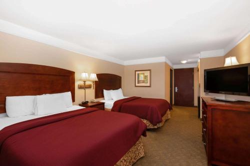 a hotel room with two beds and a flat screen tv at La Quinta by Wyndham Dodge City in Dodge City