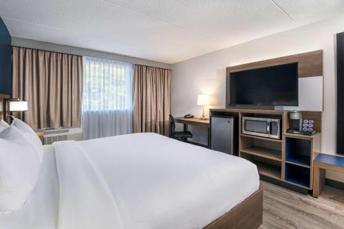 a hotel room with a bed and a flat screen tv at Comfort Suites Kingston Central in Kingston