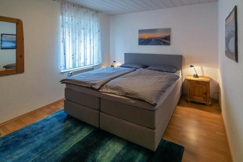 - une chambre avec un grand lit et un tapis bleu dans l'établissement Strandflieder, à Dornumersiel