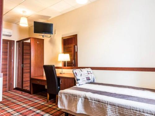 ヴロツワフにあるHotel Stara Garbarniaのベッド、デスク、テレビが備わるホテルルームです。