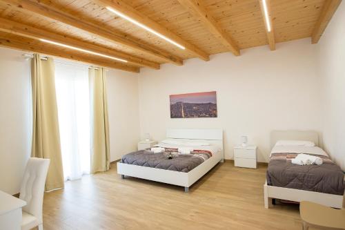 two beds in a white room with wooden ceilings at Romeo&giuliet in Marsala