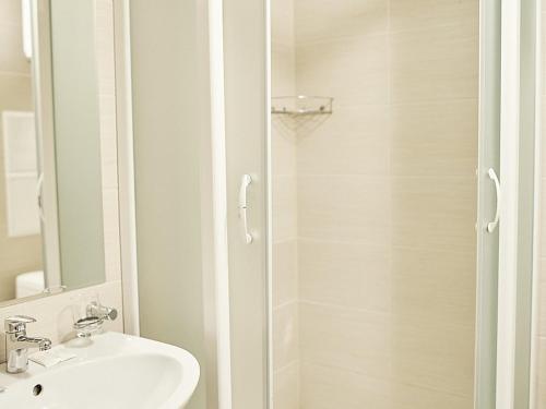 a white bathroom with a sink and a shower at Osobnyak na Teatralnoy in Kazan