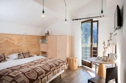 a bedroom with a bed and a table and a window at Hotel Garni Roberta in Malga Ciapela