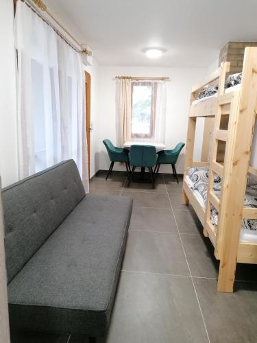 a living room with a couch and a table and bunk beds at Chaty a Apartmány Hracholusky Kemp Kosatka in Pňovany