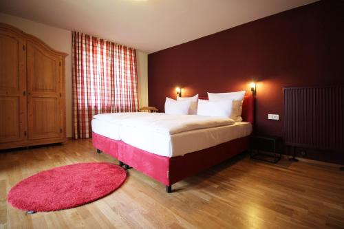 a bedroom with a large bed with a pink rug at Hotel Askania 1927 in Bad Wiessee