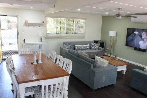a living room with a table and a couch at Little Ray on Sunshine. Hamptons style beachhouse in Woorim