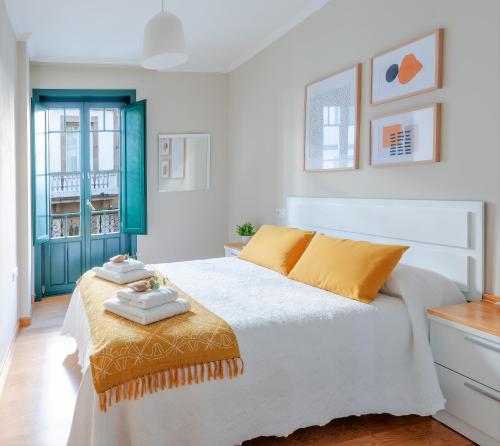 een slaapkamer met een groot wit bed met gele kussens bij ***** Solaina das Burgas ***** en el Casco Viejo in Ourense