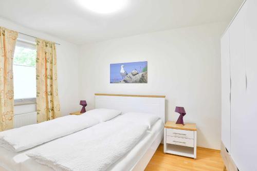 een witte slaapkamer met 2 bedden en een raam bij Ferienwohnung Möwe in Lanken