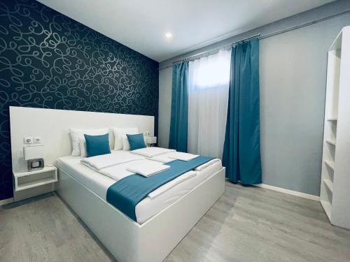 sypialnia z łóżkiem z niebieską ścianą w obiekcie Thermal Family w mieście Makó