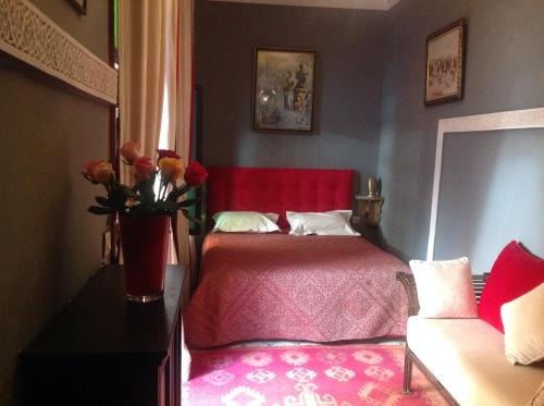 a bedroom with a red bed and a vase of flowers at Riad Syba in Marrakech