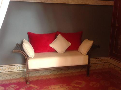 a couch with red and white pillows on it at Riad Syba in Marrakech