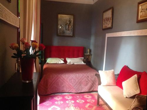 a bedroom with a red bed and a couch at Riad Syba in Marrakech