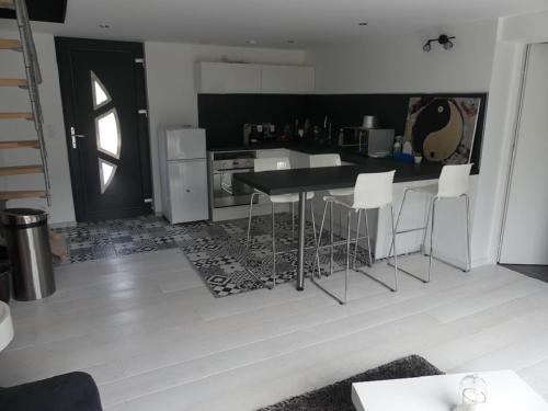 a kitchen with a table and some white chairs at Appartement 30 m2 neuf + terrasse in Brindas