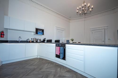 プリマスにあるThe Kensington Suiteのキッチン(白いキャビネット、黒いカウンタートップ付)