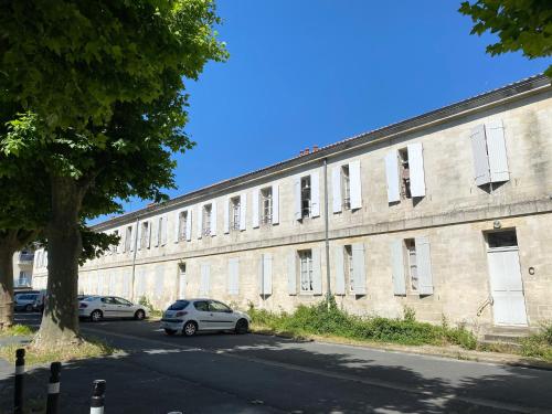 un grand bâtiment en briques avec des voitures garées devant lui dans l'établissement Logis B21, à Rochefort
