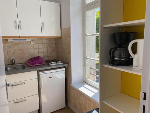 a small kitchen with white cabinets and a window at Logis B21 in Rochefort