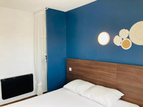 - une chambre dotée d'un mur bleu avec un lit et une télévision dans l'établissement Hotel le Provençal, à Narbonne-Plage