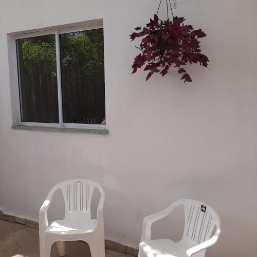 two white chairs sitting next to a window at Casa Vitória em barra de jacuipe in Campos