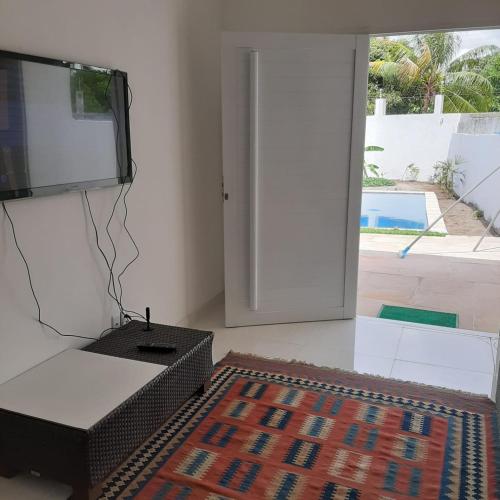 a living room with a tv and a rug at Casa Vitória em barra de jacuipe in Campos