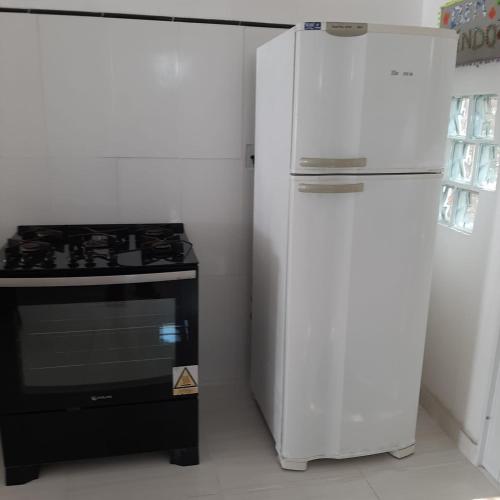a kitchen with a stove and a white refrigerator at Casa Vitória em barra de jacuipe in Campos