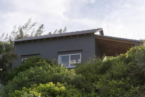 a house on a hill with trees and bushes at Coral Tree Surf Cottage - Tofinho, Tofo in Praia do Tofo