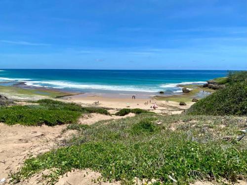 a group of people on a beach near the ocean at Coral Tree Surf Cottage - Tofinho, Tofo in Praia do Tofo